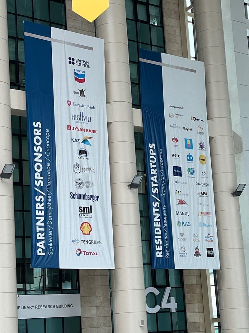 Pictures of Nazarbayev University. Note the corporate sponsorship and startup banners. The juxtaposition of banners celebrating corporate sponsorships and third party rankings with the astroturf sitting areas struck me as apt.